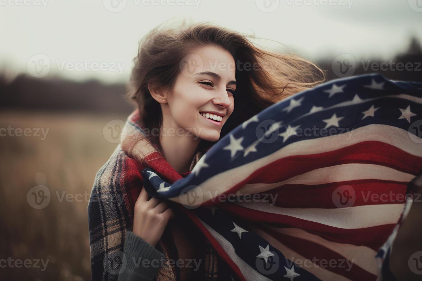 A beautiful young woman wrapped in an American flag on her neck in the field. photo