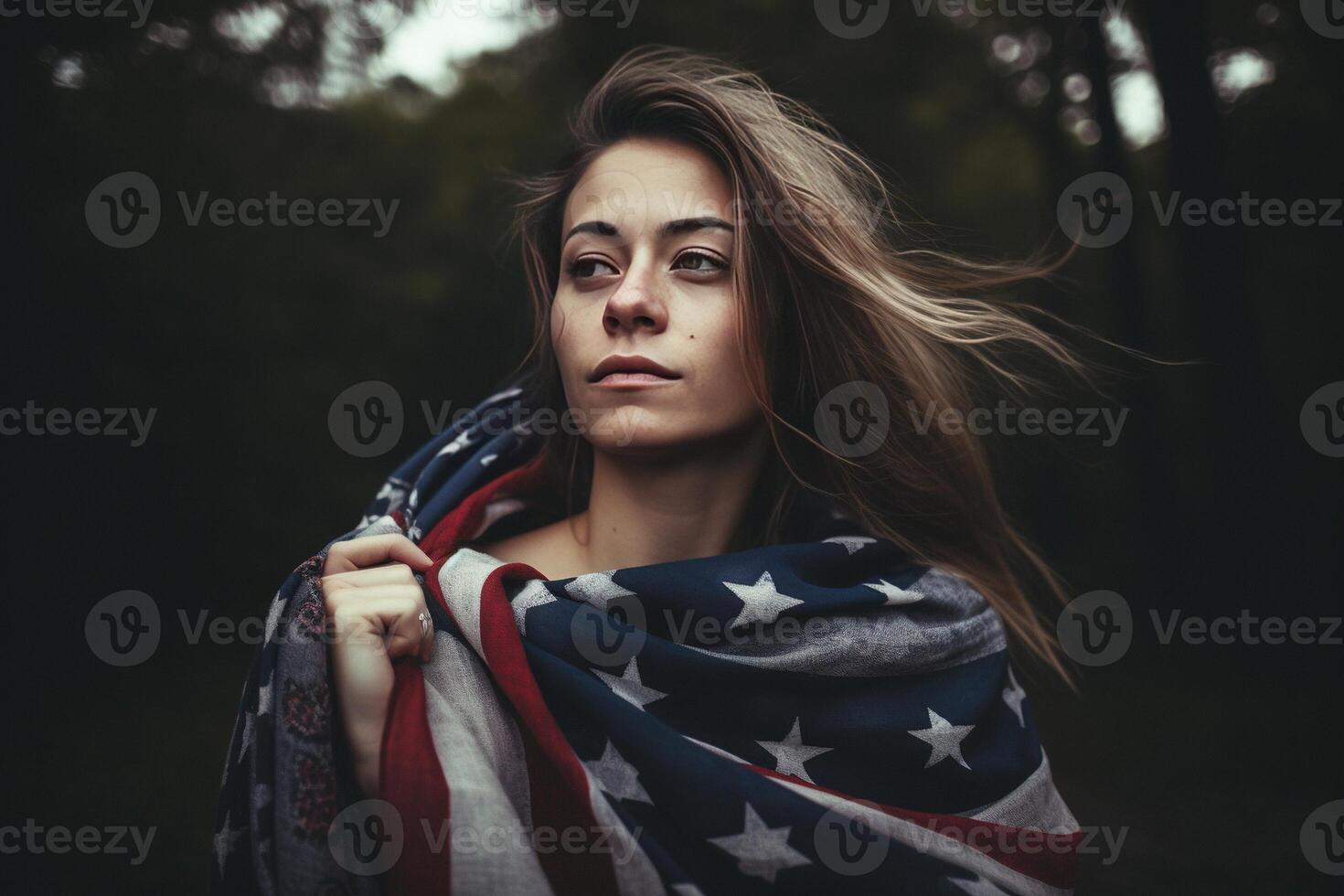 A beautiful young woman wrapped in an American flag on her neck in the field. photo