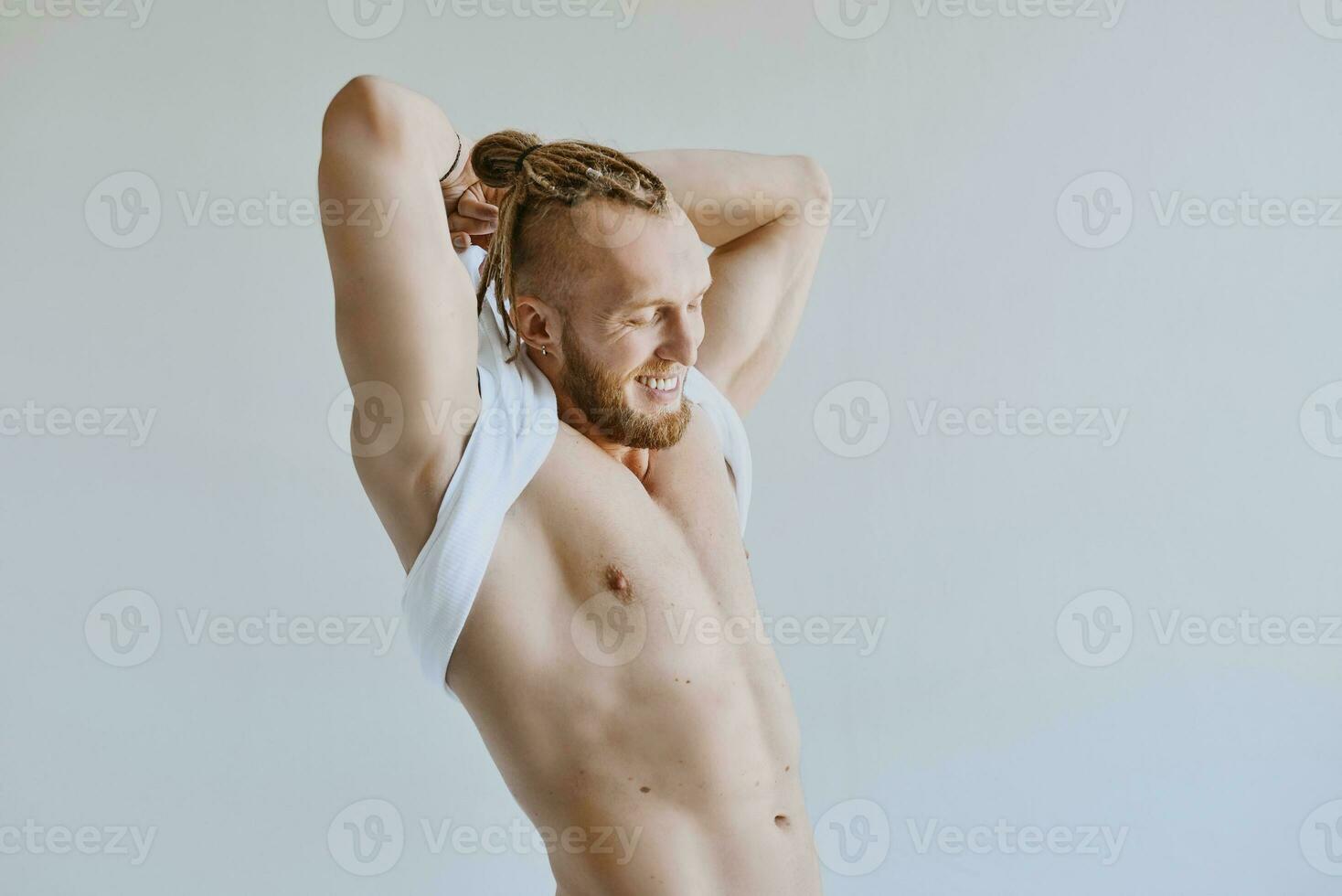 hermoso caucásico atlético riendo joven hombre tomando apagado blanco camiseta. aptitud física, culturismo, juventud concepto foto