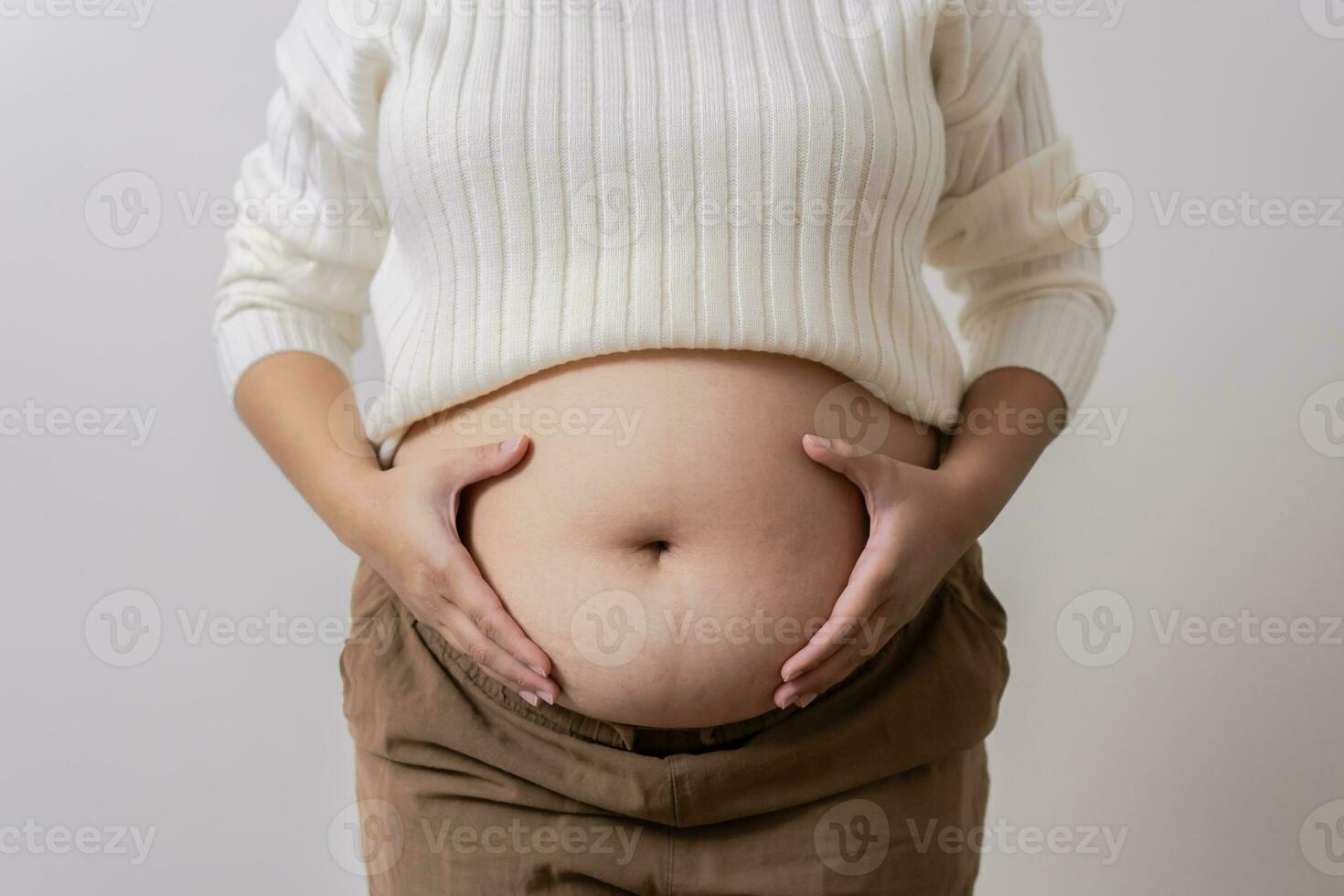 An obesity using measuring tape to show the real size. Chubby fat woman using measure tape at belly. Real size woman after gave birth to baby, real skin with wrinkles and scars. photo