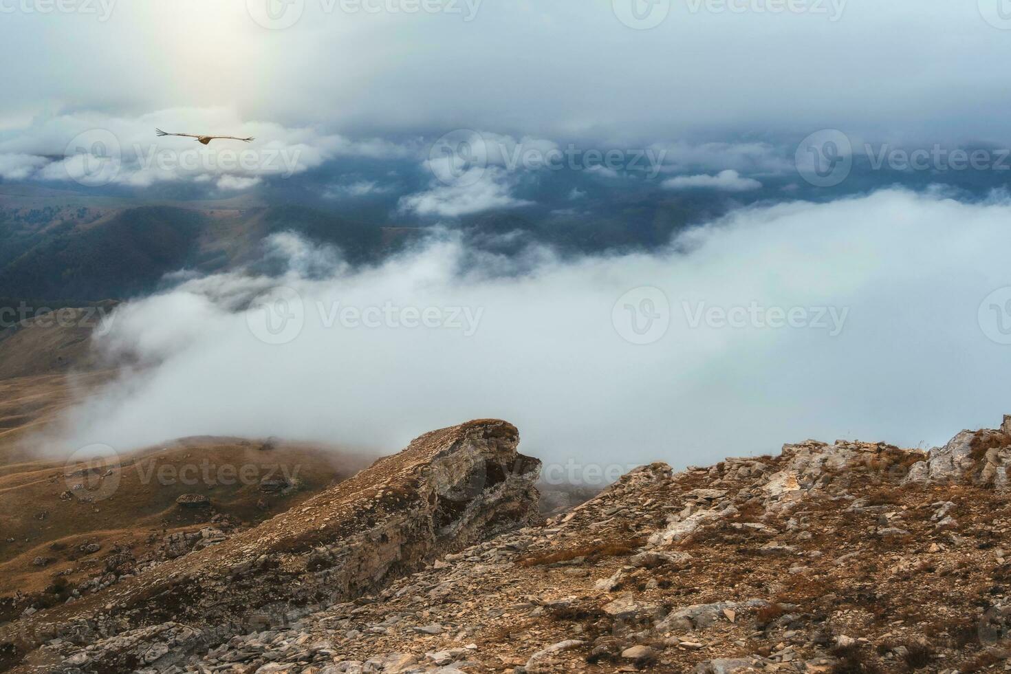 Foggy mountain view from cliff at very high altitude. Scenic alpine landscape with beautiful sharp rocks and couloirs  in sunrise. Beautiful scenery on abyss edge with sharp stones. photo