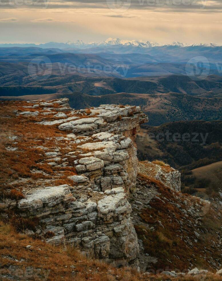 amanecer ver de bermamyt meseta rocas montañas en el borde de un acantilado en el distancia en dramático Mañana. atmosférico paisaje con siluetas de montañas. karachay-cherkesia, Cáucaso, Rusia. foto