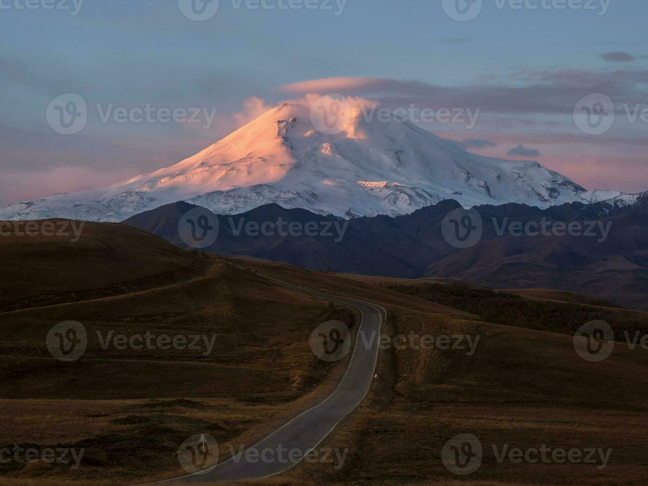 el ruta a el amanecer elbrús rosado majestuoso amanecer terminado montar elbrús Nevado montaña picos a amanecer. puesta de sol en magenta tonos atmosférico púrpura paisaje con un alta altitud Nevado montaña valle. foto