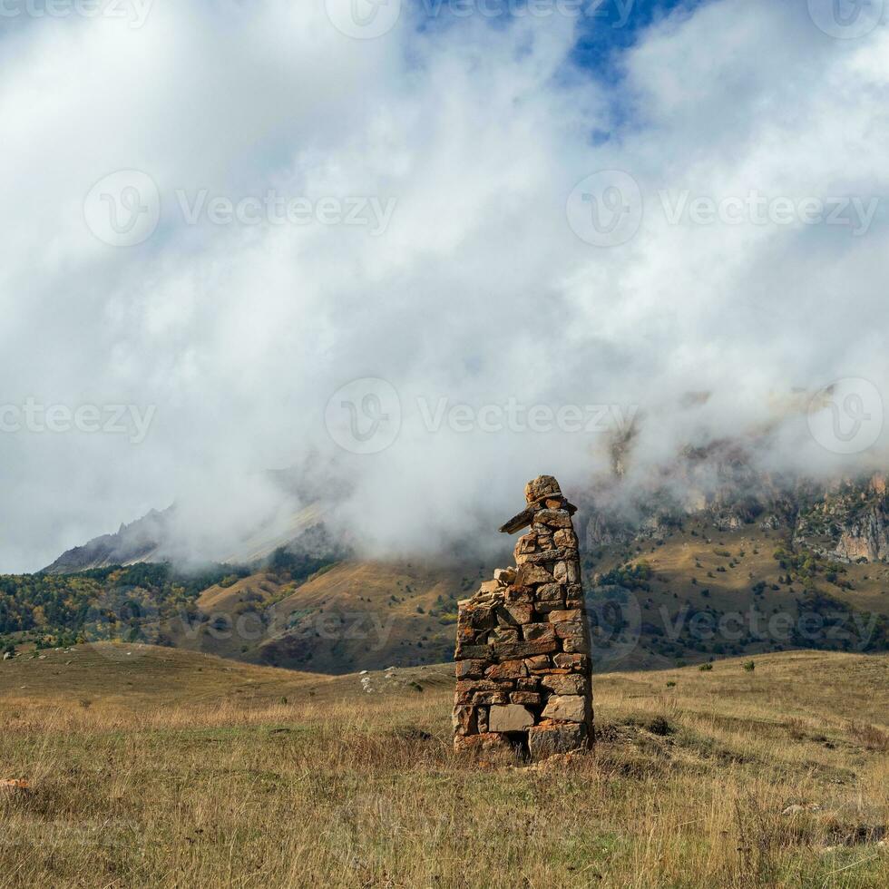 An ancient stone idol on the background of misty mountains. Tombstones made of stone. Stur-Digora region. North Ossetia. photo