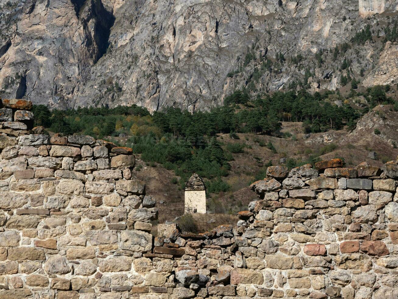 Old stone wall with arched passage. Old Pyaling towers complex, one of the largest medieval castle-type tower villages, located on the extremity of the mountain range in Ingushetia, Russia. photo