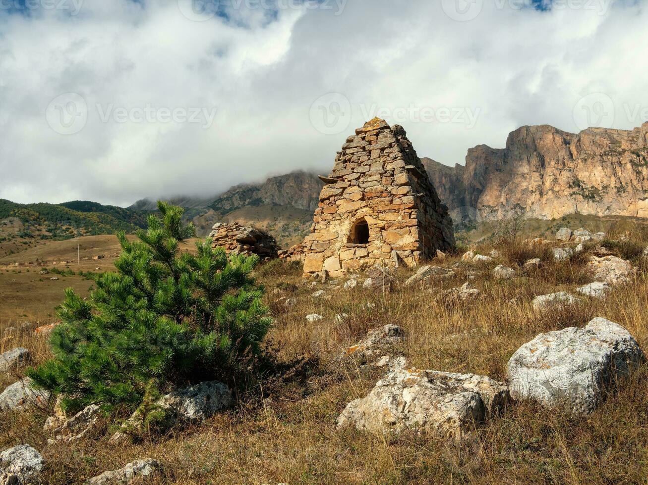 Old stone tomb, a crypt on the top of a mountain. Old Ossetian family crypt in the misty mountains. Russia. photo