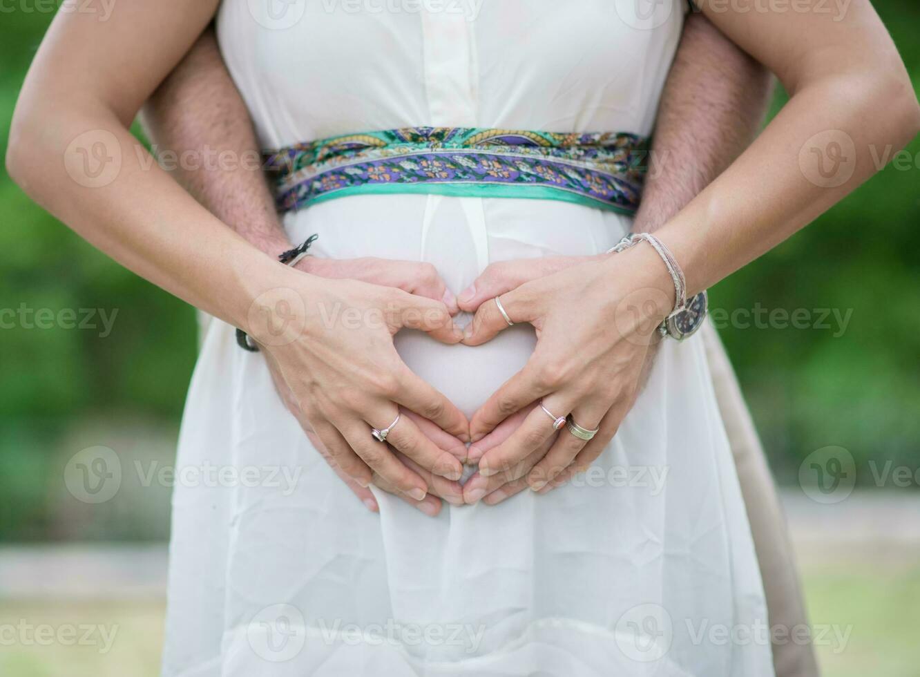 Image of parent's hands as a heart shape on belly photo