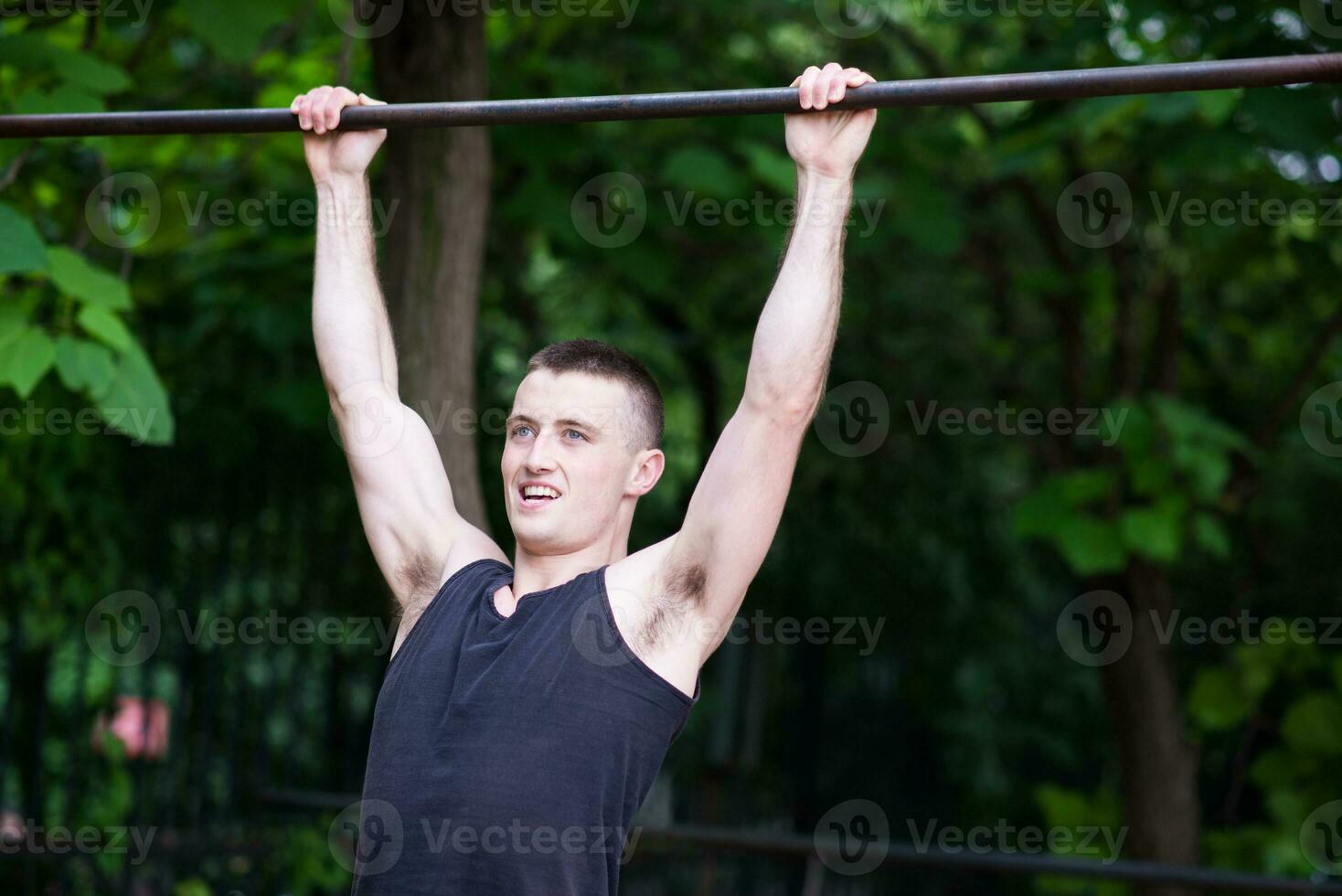 strong man doing pull-ups on a bar outdoor photo