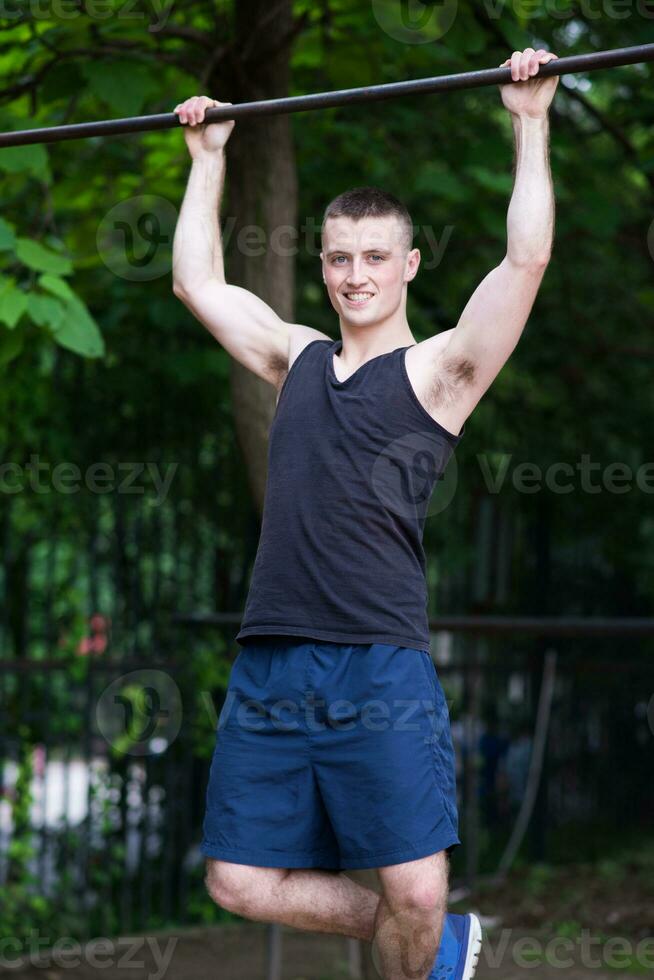 strong man doing pull-ups on a bar outdoor photo