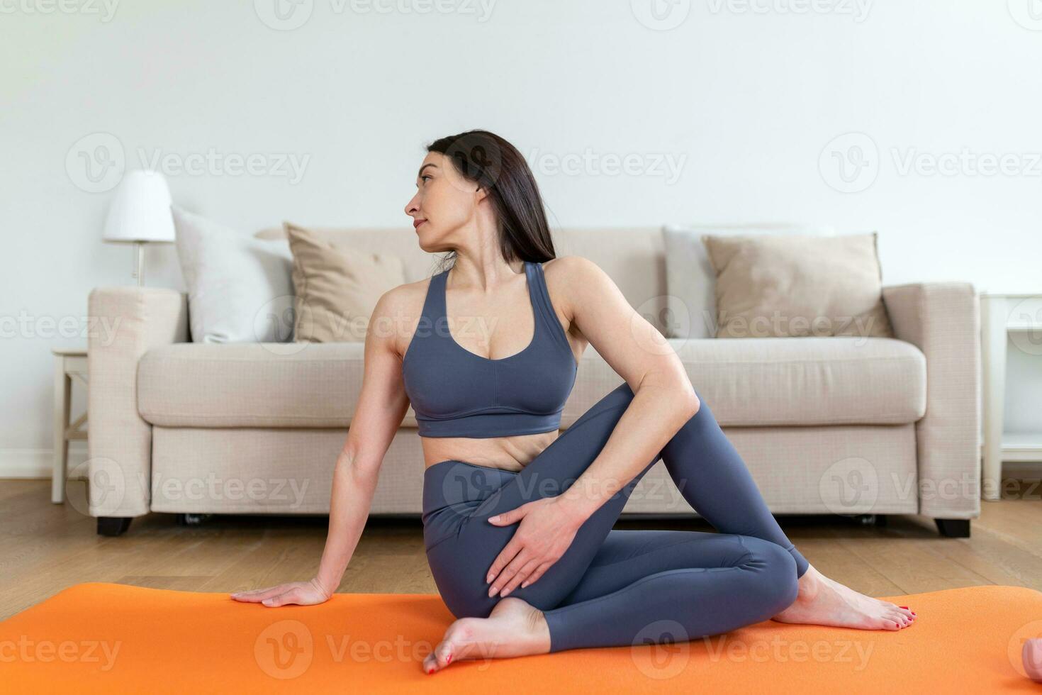 Asian sporty woman practicing yoga at home doing half lord of the fishes pose. Ardha Matsyendrasana. Healthy lifestyle concept photo