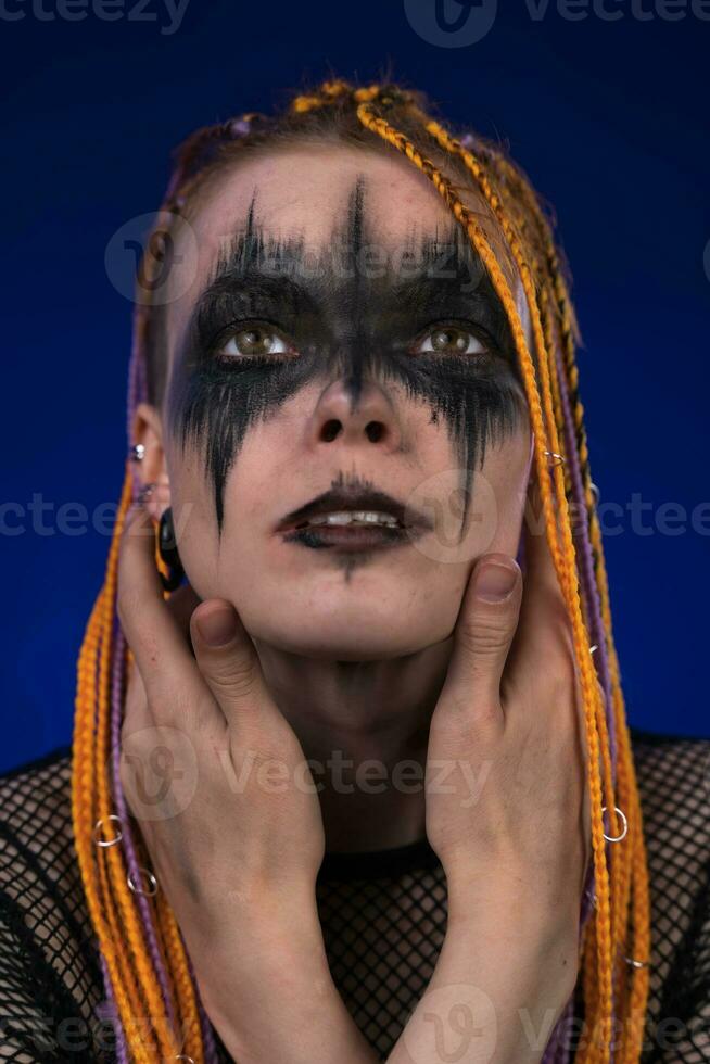 Portrait of young woman with creative horror make up painted on face and dreadlocks hairstyle photo