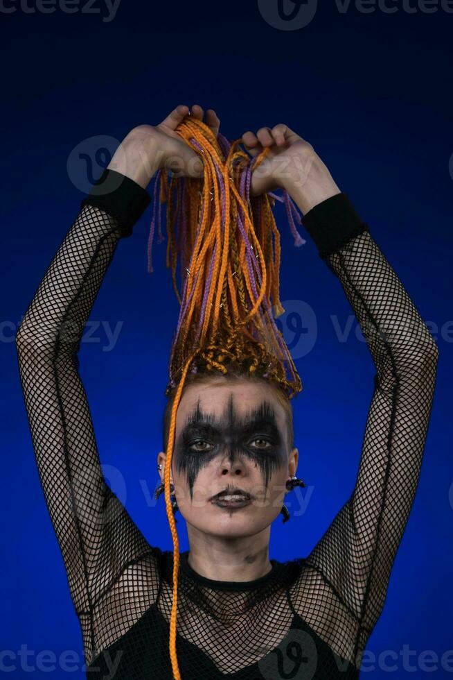 Fine art portrait of woman with dreadlocks hairstyle and horror black stage make-up painted on face photo