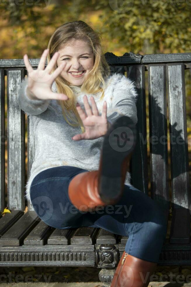 Beautiful young woman in an autumn park sits on a bench. photo