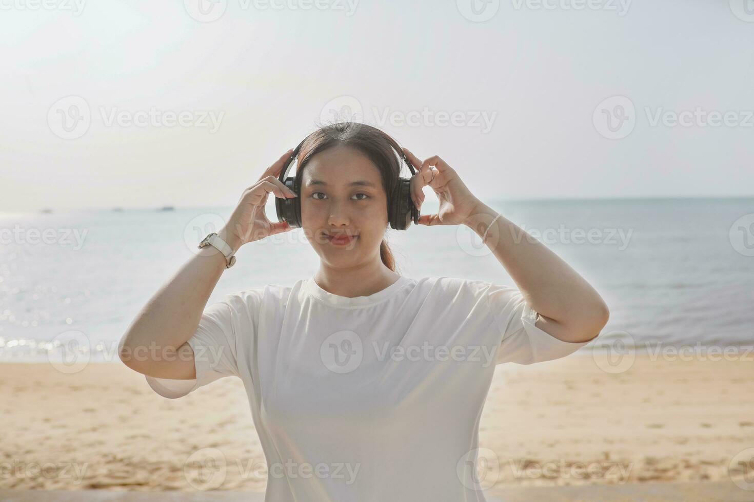portrait of asian younger woman wearing headphone standing beside sea beach photo