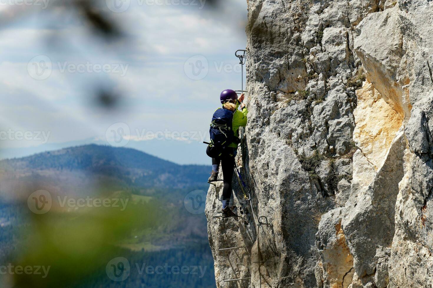 A person climbing a via ferrata route on a vertical rock wall. Sports life in the mountains. Active life. Climber using proper equipment for security. Via Ferrata Sokolov put Romanija in BiH. photo