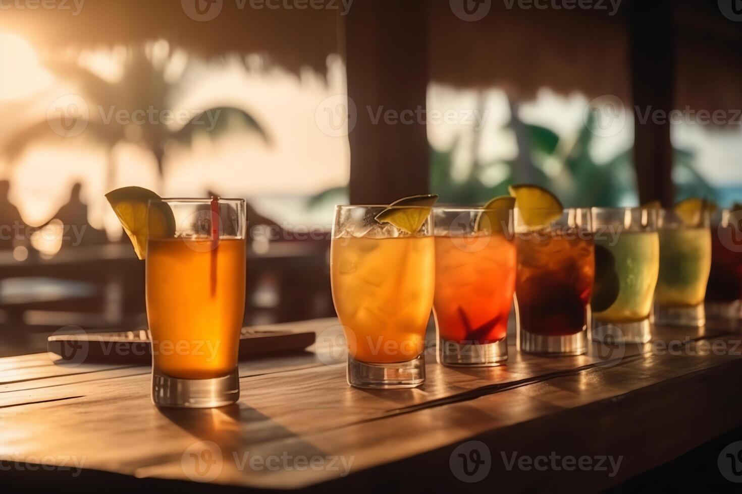 Wooden table and glasses with cocktails in the eground and soft focus summer beach and a bar in the blurred background tropical resort banner as a tropical holiday concept. photo