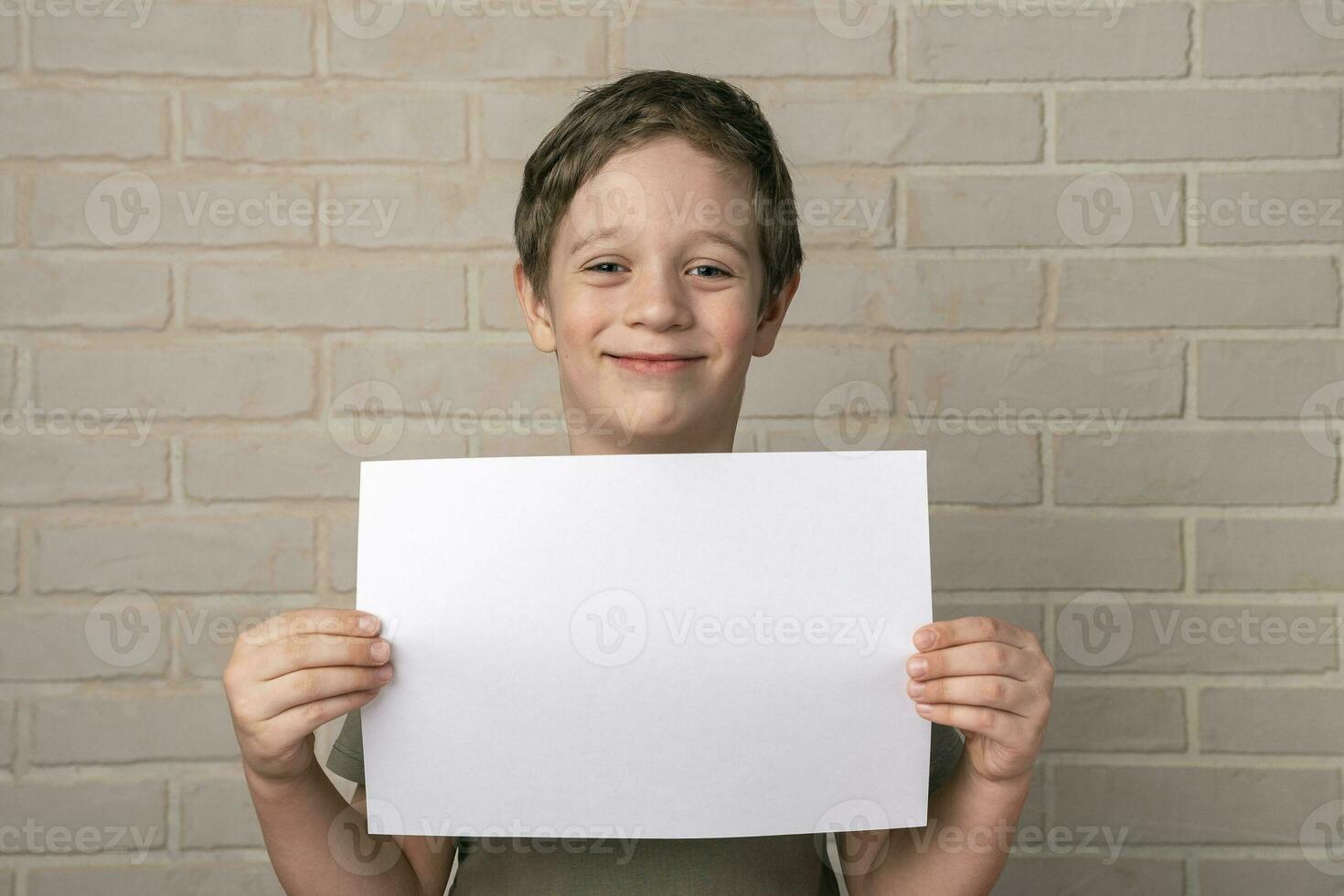 A cheerful smiling 5-year-old European boy holds an empty poster above his head photo