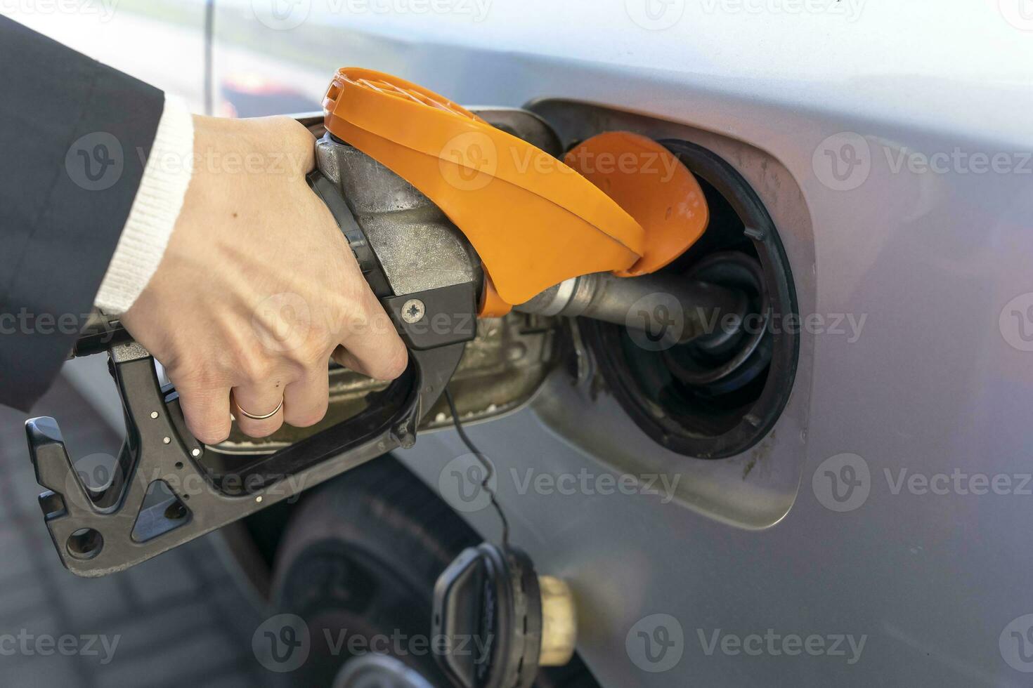 a woman's hand holds a refueling gun in the neck of the tank of the car. the girl refuels the car photo