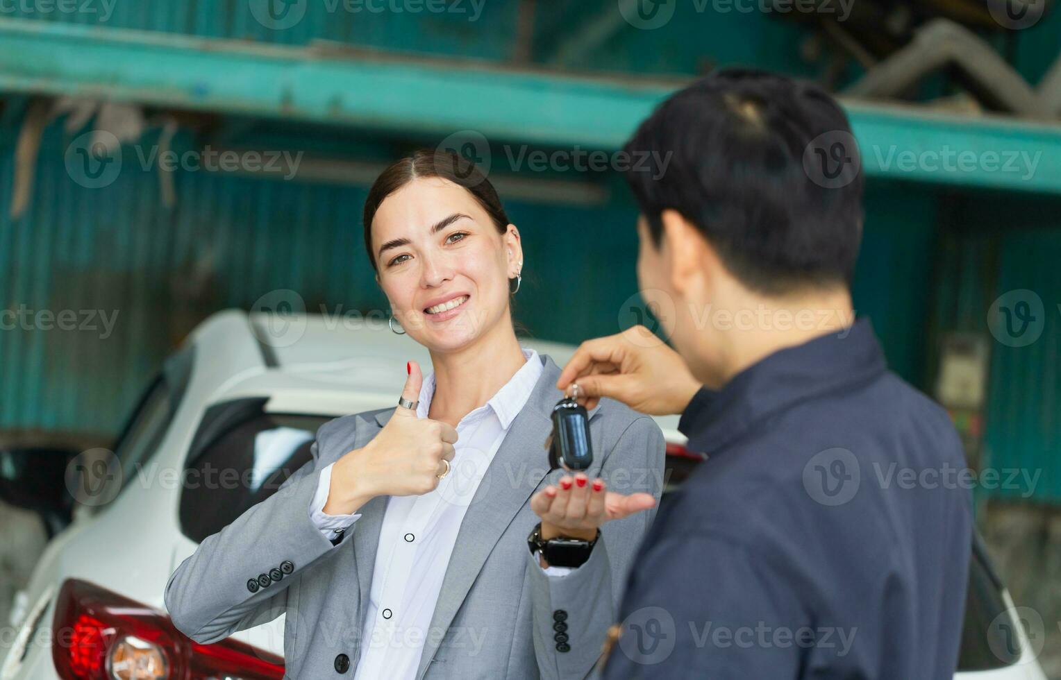 Auto mechanic repairman handing car remote key to client, Mechanic returns the key to the satisfied custumer, Car repair and maintenance concepts photo