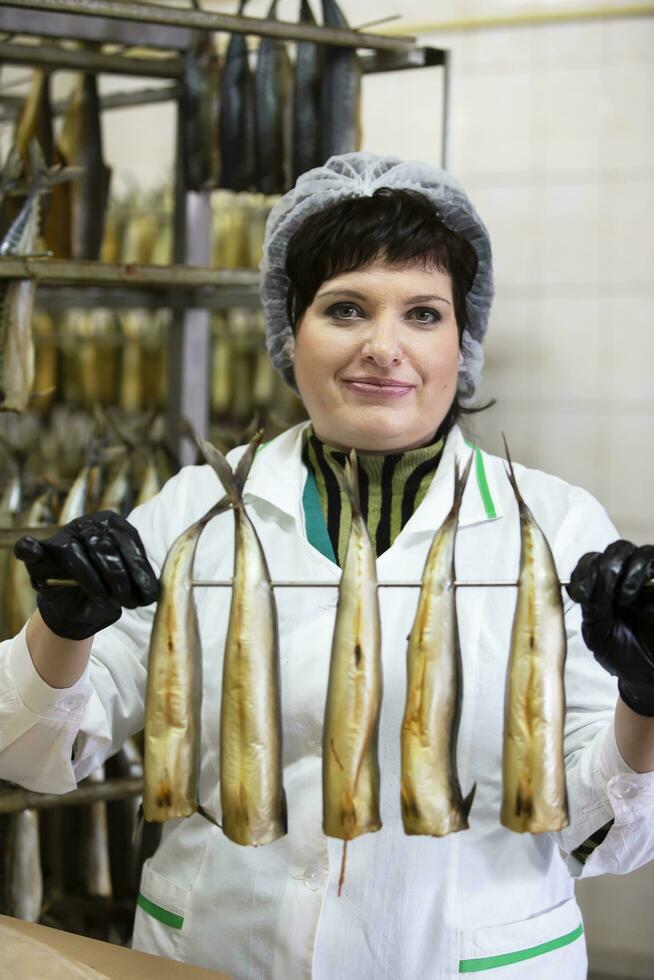 September 18, 2020. Belarus, Gamil. Fish factory.Fish factory worker holds smoked fish. photo