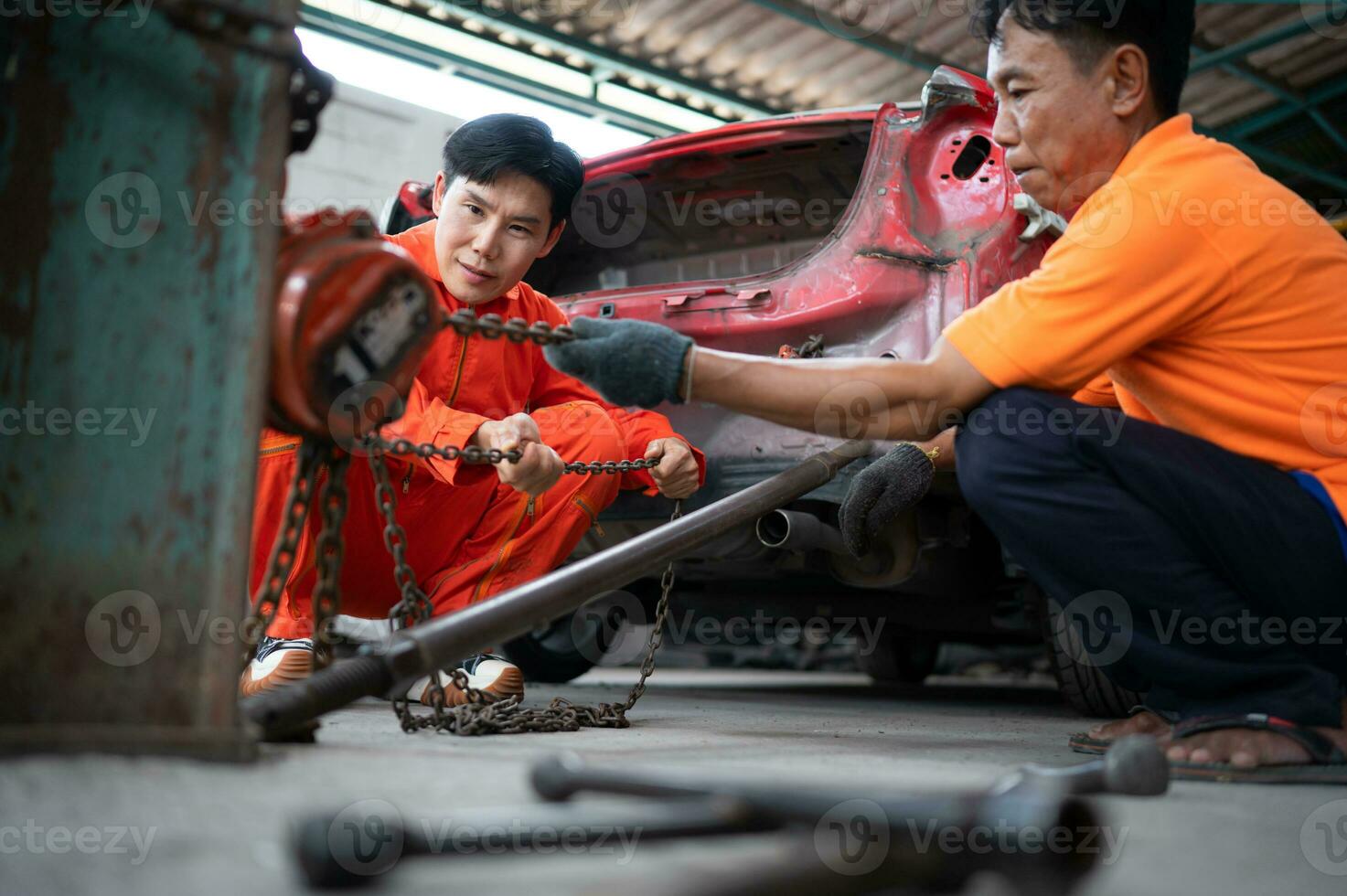 To return the automobile body to its former shape, an auto repair mechanic uses a machine to pull the car body caused by a heavy collision until it is deformed. photo