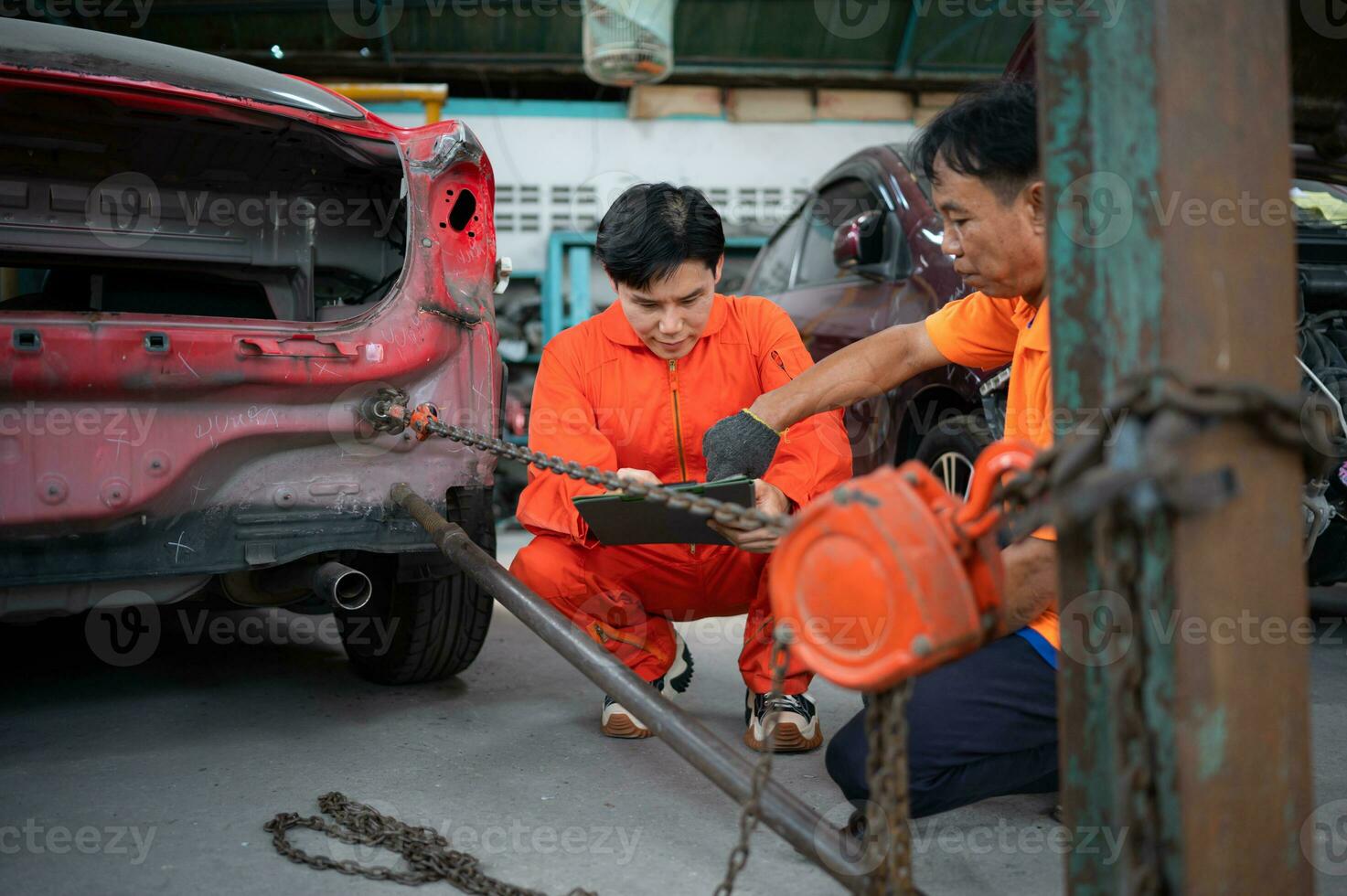 To return the automobile body to its former shape, an auto repair mechanic uses a machine to pull the car body caused by a heavy collision until it is deformed. photo