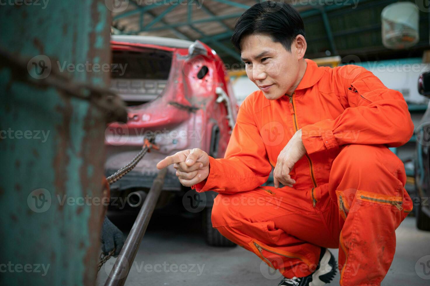 To return the automobile body to its former shape, an auto repair mechanic uses a machine to pull the car body caused by a heavy collision until it is deformed. photo