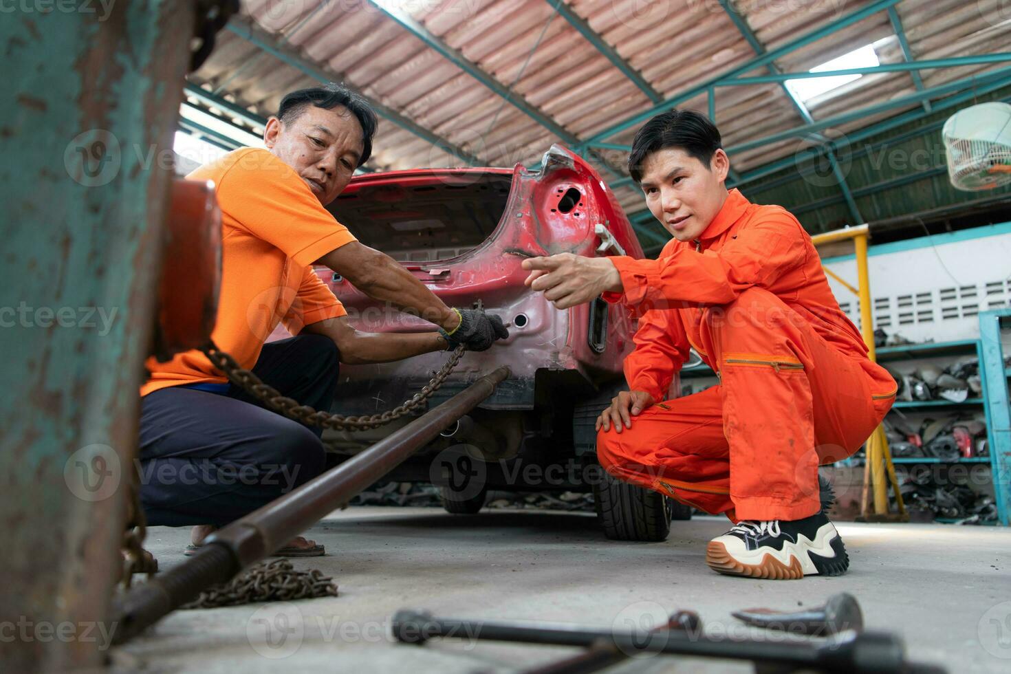 To return the automobile body to its former shape, an auto repair mechanic uses a machine to pull the car body caused by a heavy collision until it is deformed. photo
