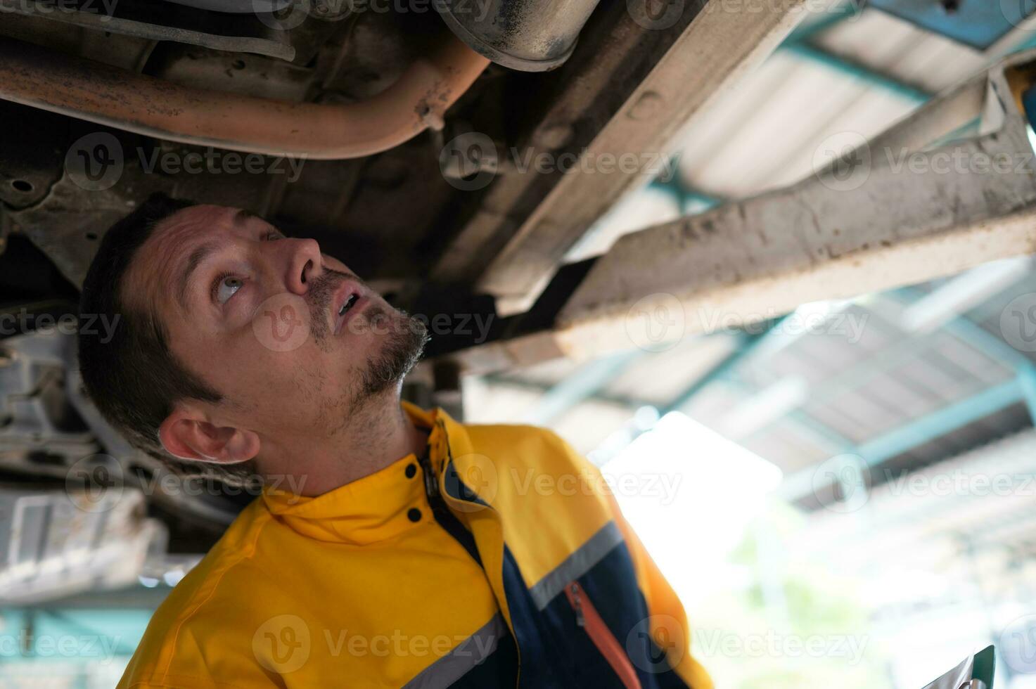 Auto repair mechanic the undercarriage of the car is being inspected for damage caused by heavy collisions. photo