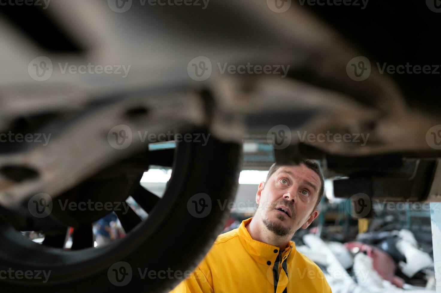 Auto repair mechanic the undercarriage of the car is being inspected for damage caused by heavy collisions. photo