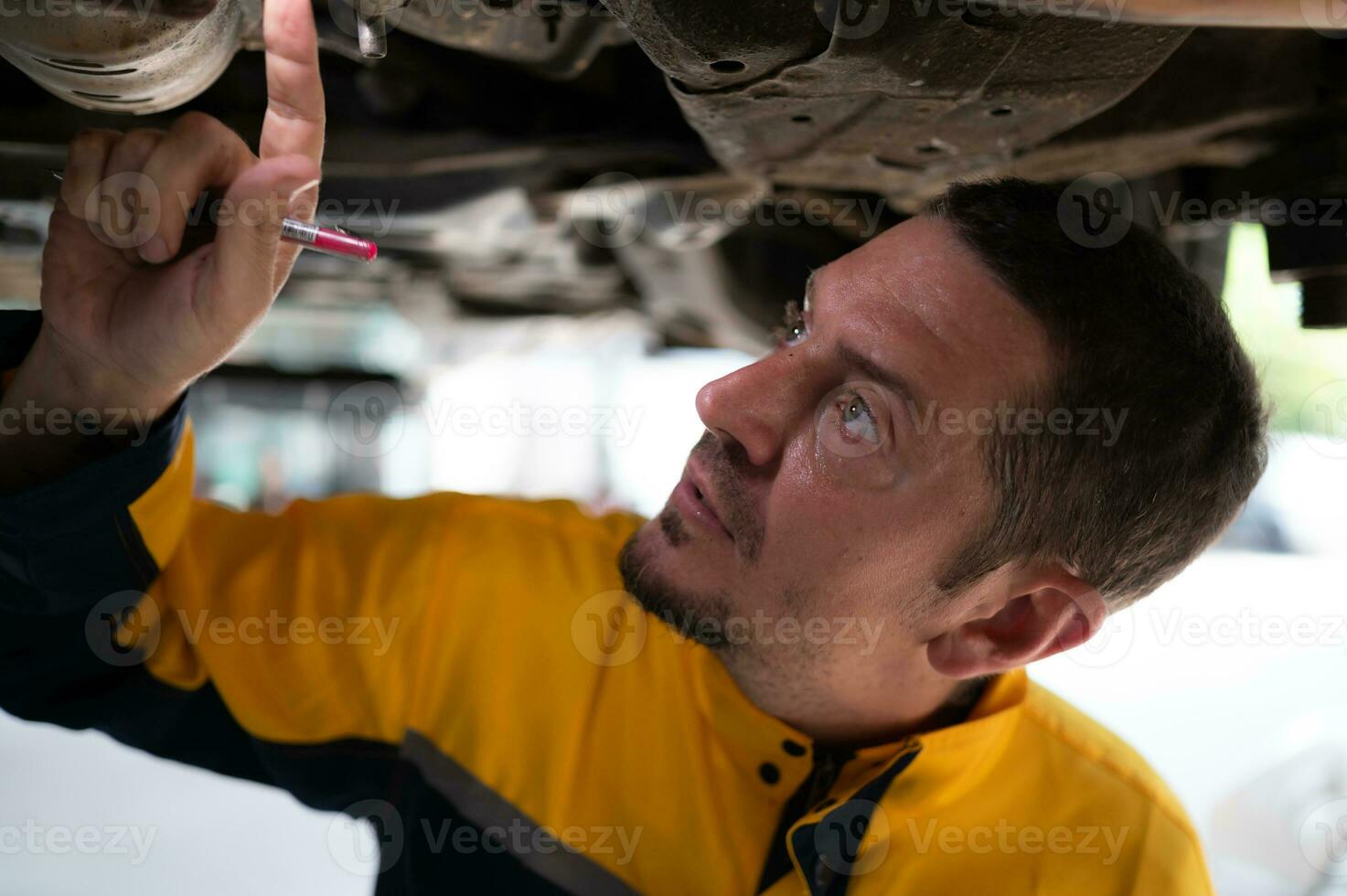Auto repair mechanic the undercarriage of the car is being inspected for damage caused by heavy collisions. photo