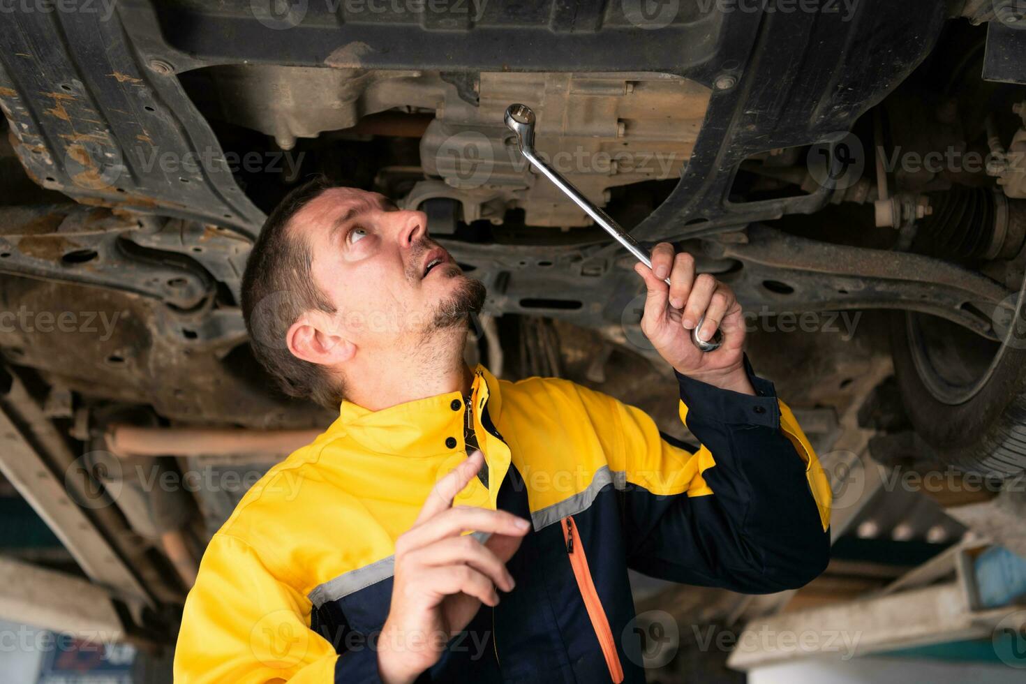 Auto repair mechanic the undercarriage of the car is being inspected for damage caused by heavy collisions. photo