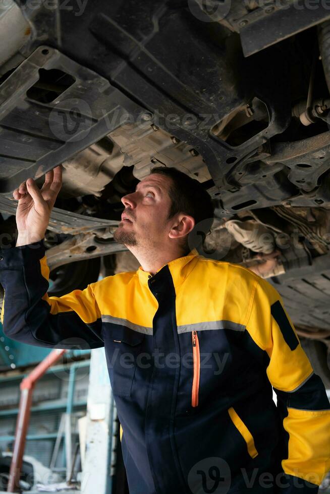 Auto repair mechanic the undercarriage of the car is being inspected for damage caused by heavy collisions. photo