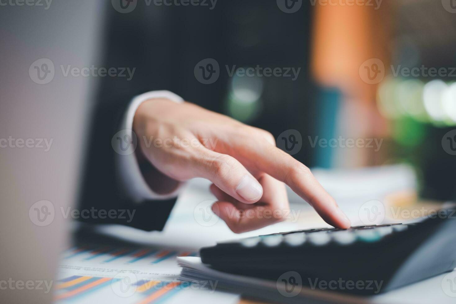 Businessman using a calculator to calculate numbers ,profit and loss statement review of company performance, cost analysis ,financial paperwork ,account checking ,chart analysis and statistical data photo