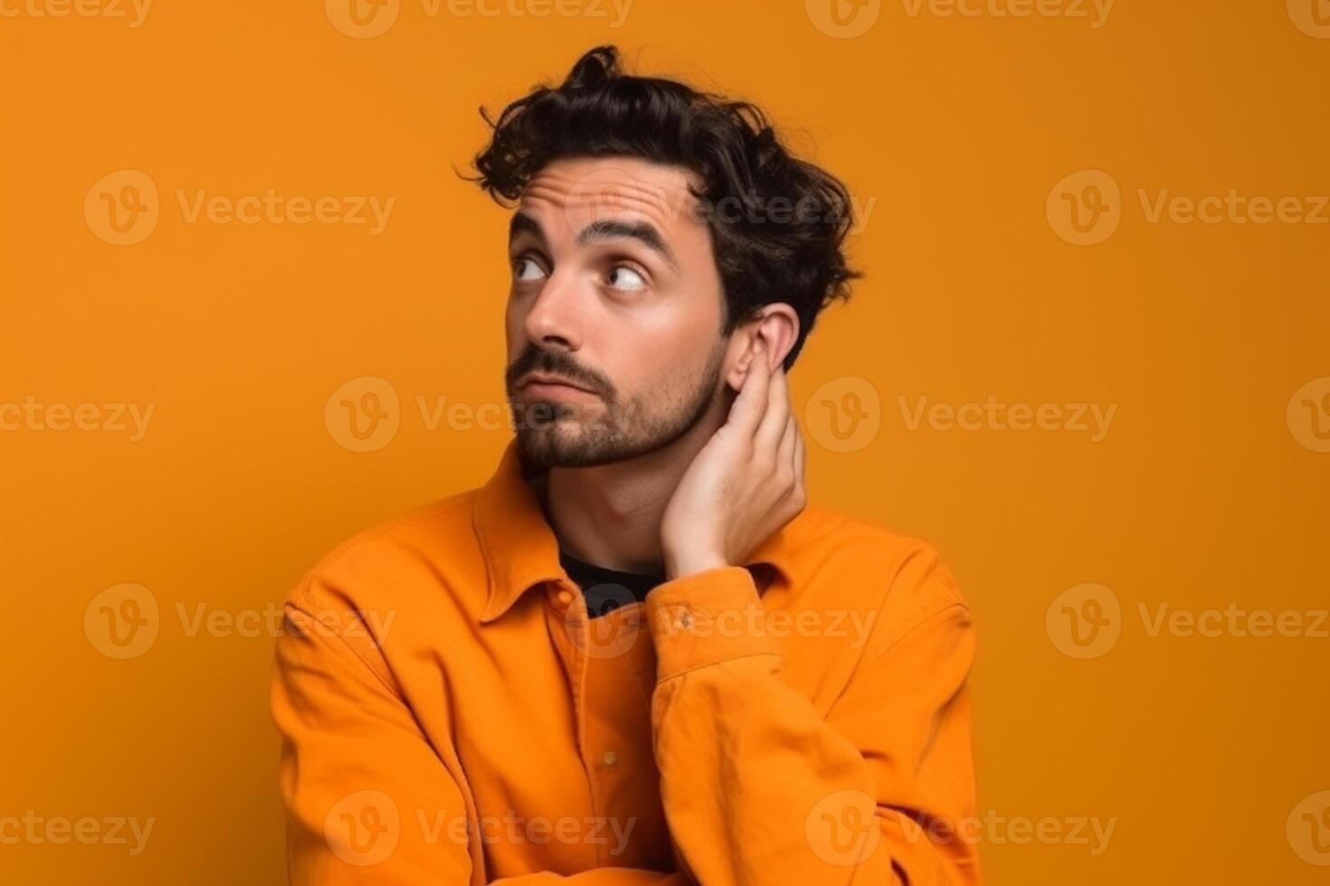 A man is being photographed on a solid background with a look of confusion on his face. photo