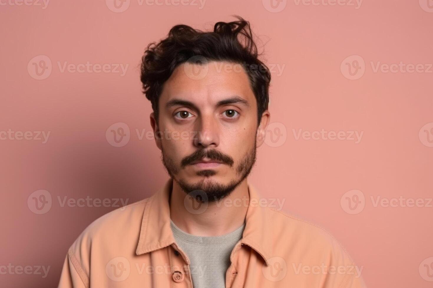 A man is being photographed on a solid background with a look of confusion on his face. photo