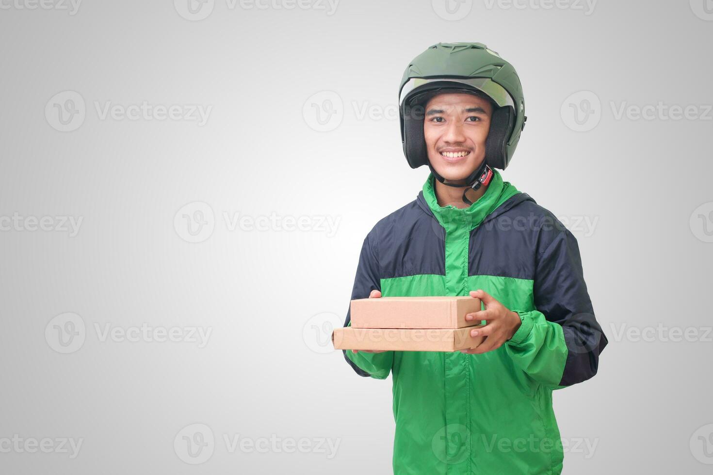 Portrait of Asian online courier driver wearing green jacket and helmet delivering package and box for customer. Isolated image on white background photo
