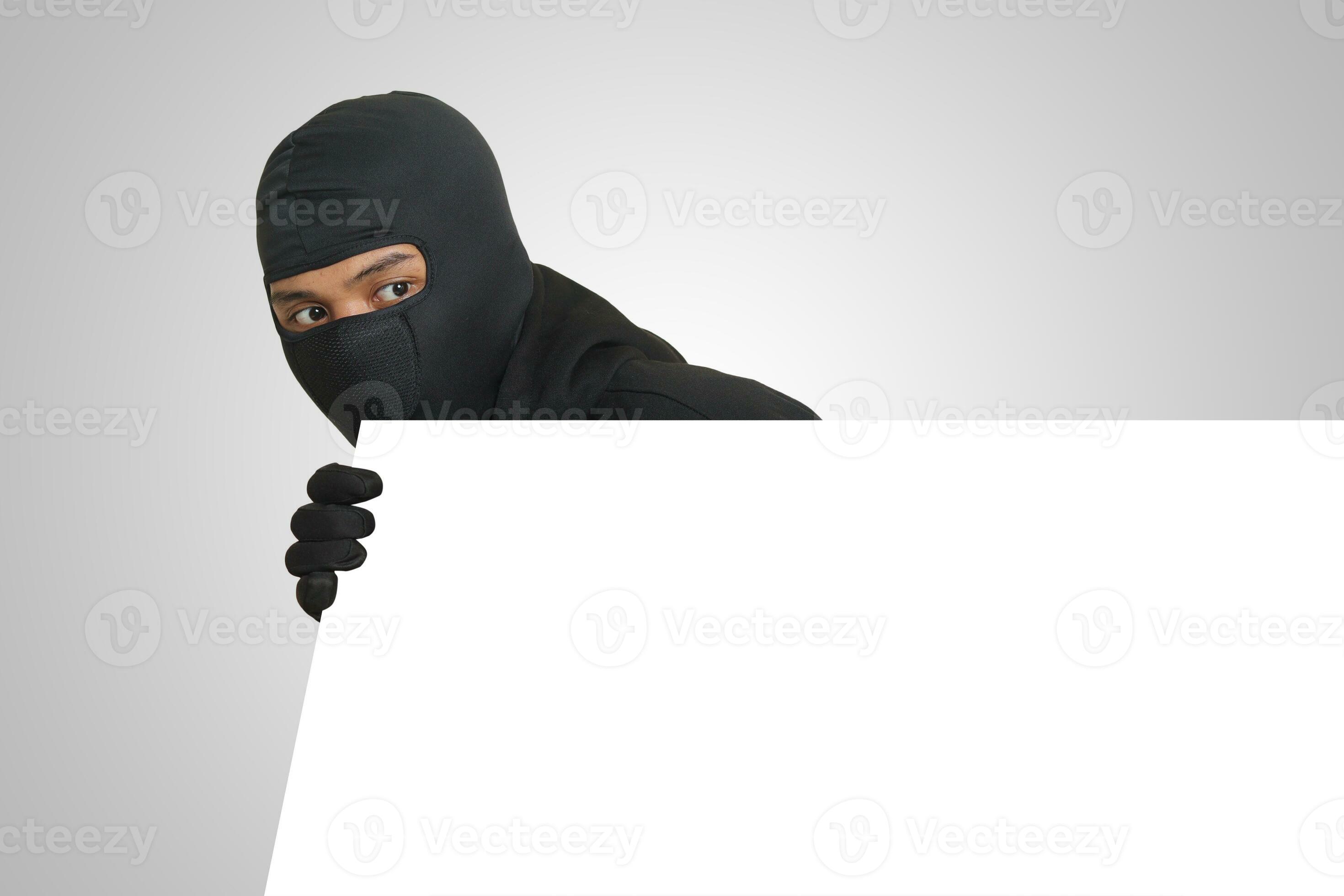Mysterious thief wearing black hoodie hiding behind wall, sneaking, and