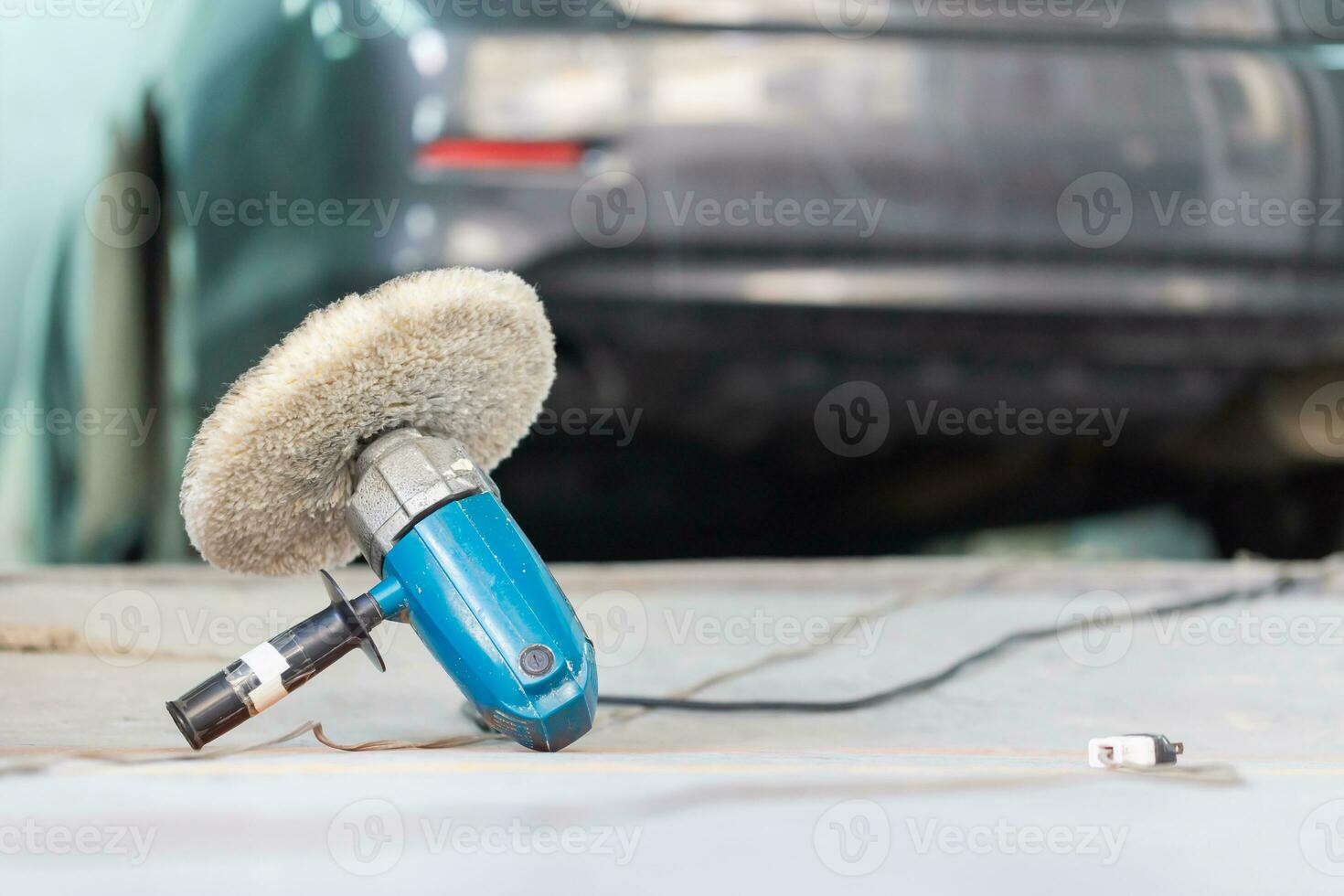 Polishing machine tool, Grinding tool on the floor with blurred car in chamber, Garage painting car service repair and maintenance photo