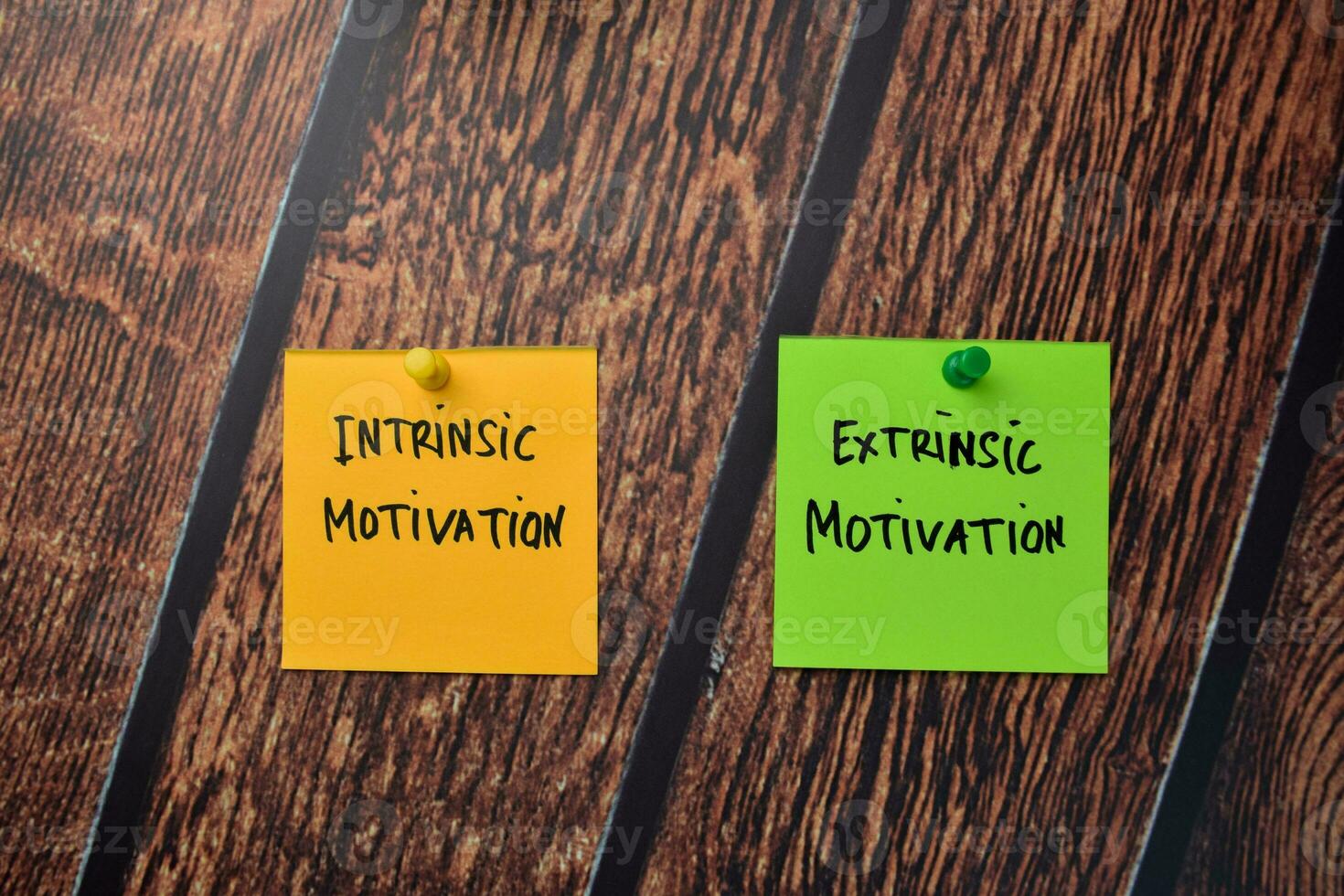 Intrinsic Motivation and Extrinsic Motivation write on sticky notes isolated on office desk. photo