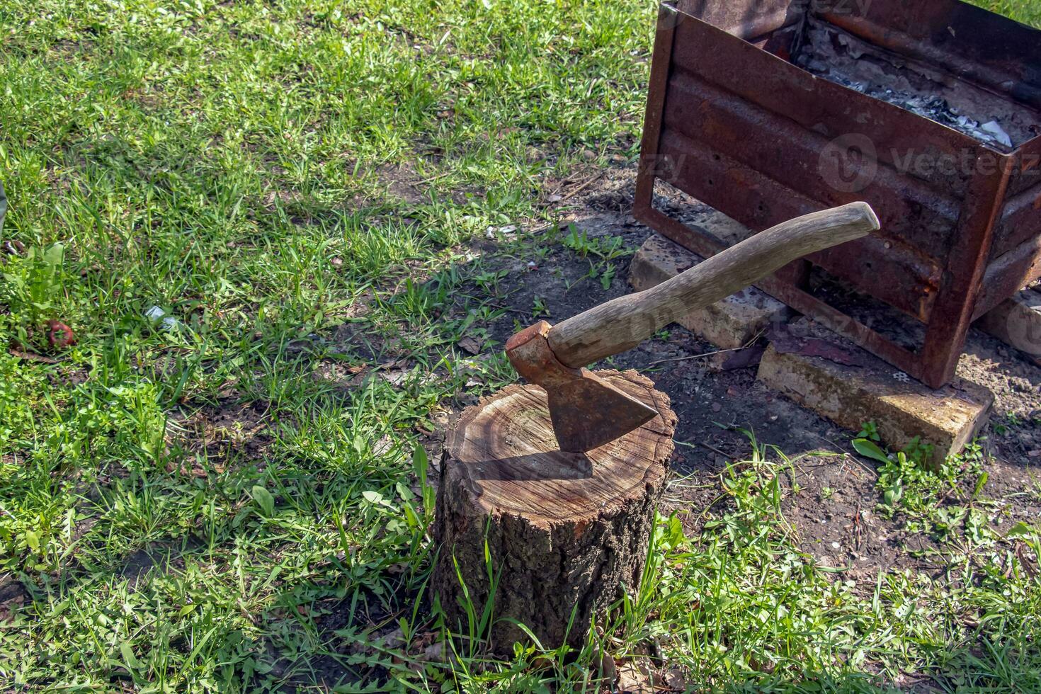 The wood chopper sticks out in wooden hemp. Ax and ax handle. Woodworking. Deforestation by a sharp axe. Ax to chop wood. Rusty but very sharp forester's ax or carpenter's axe. photo