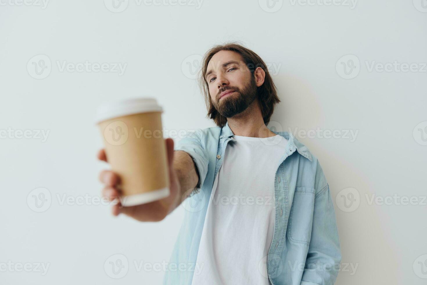 Freelance Millennial man with a beard drinking coffee from a recycled cup in stylish hipster clothes white T-shirt blue jeans and shirt on a white background photo