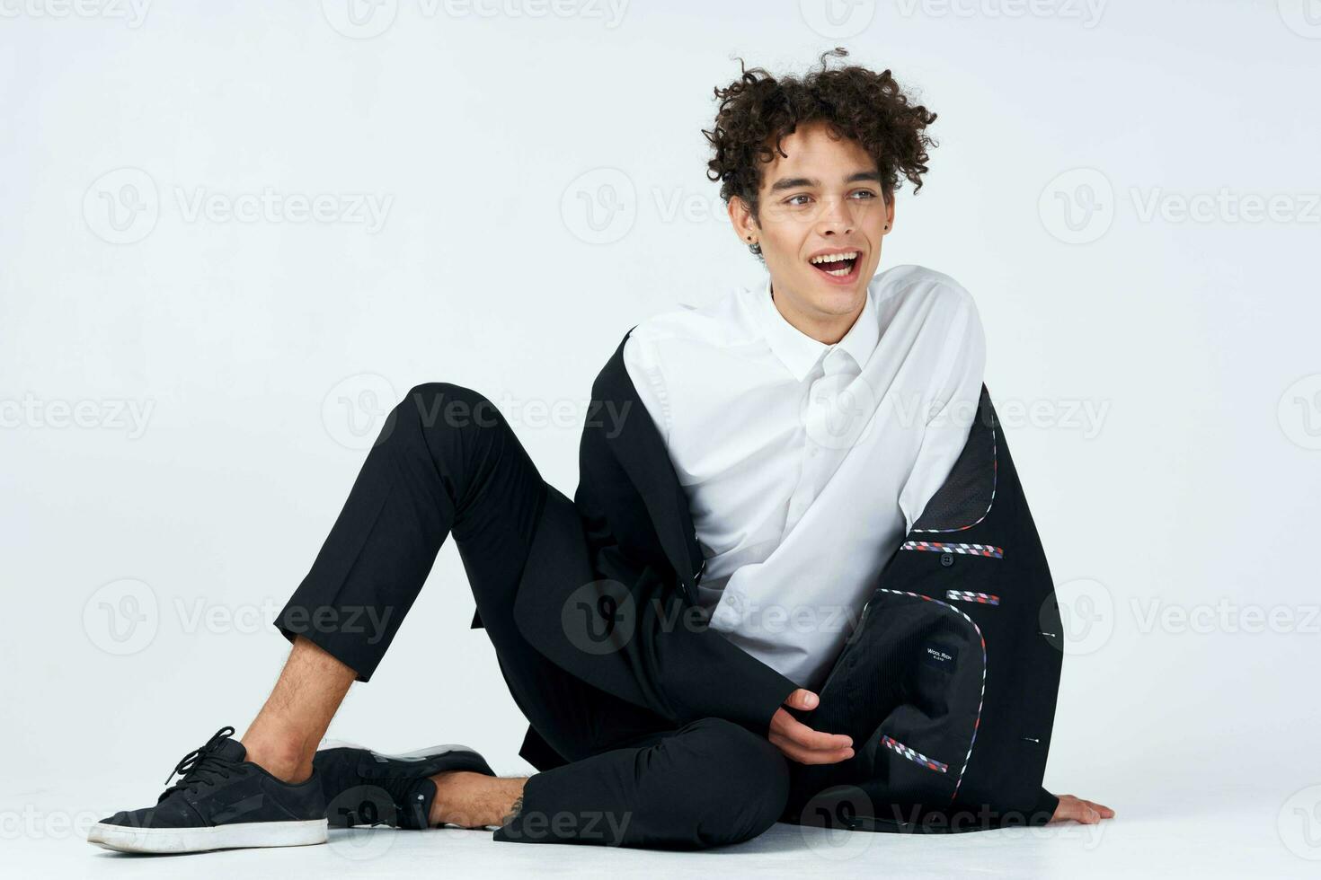 guy in a white shirt sitting on the floor curly hair photo