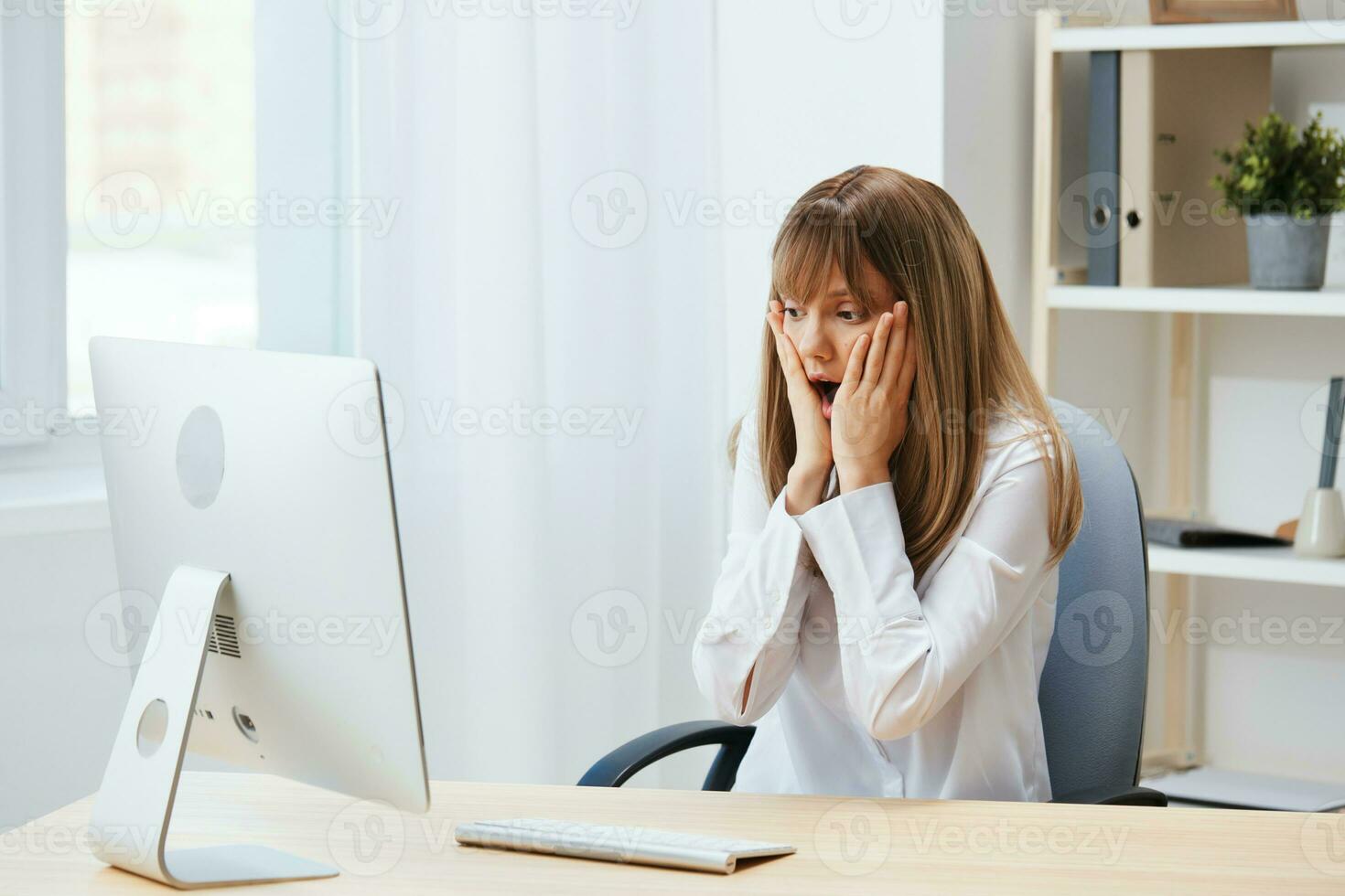 Shocked upset adorable blonde businesswoman worker touch chin both hands thinking of problem solution in light modern office. Employee work on computer online pondering or making decision. Copy space photo