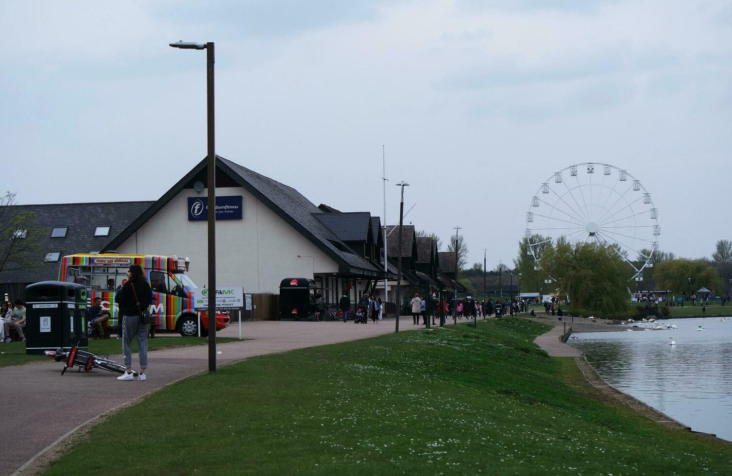 Low Angle View of Willen Lake Park with Local and Tourist Public Enjoying the Beauty of Lake and Park by Walking Around with Their Families. Footage Was Captured on 09-April-2023 at Milton Keynes UK photo