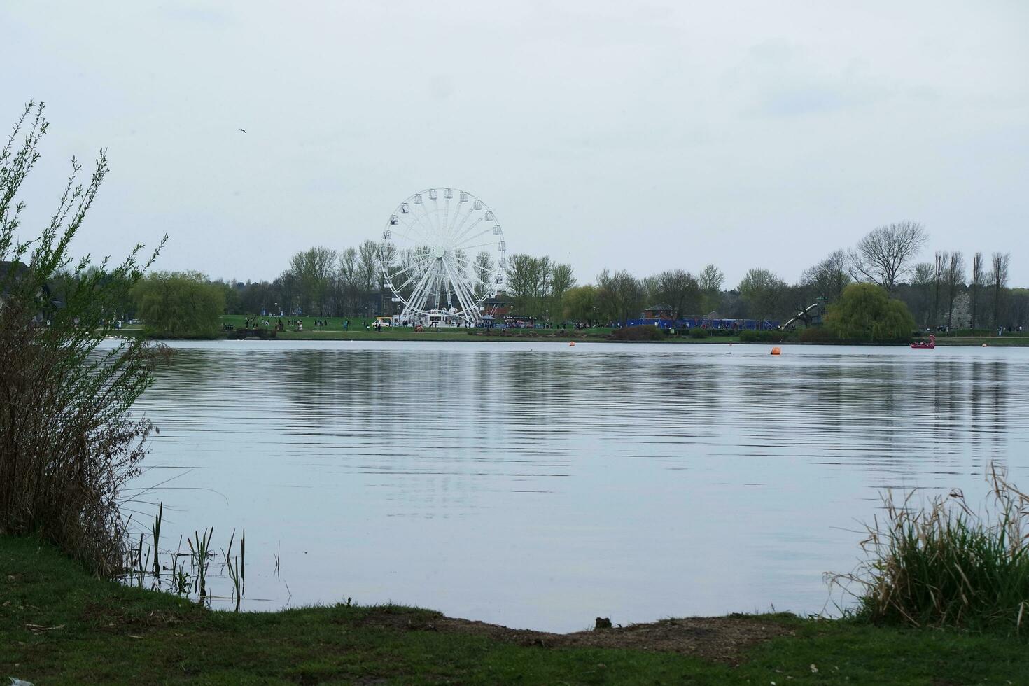 Low Angle View of Willen Lake Park with Local and Tourist Public Enjoying the Beauty of Lake and Park by Walking Around with Their Families. Footage Was Captured on 09-April-2023 at Milton Keynes UK photo