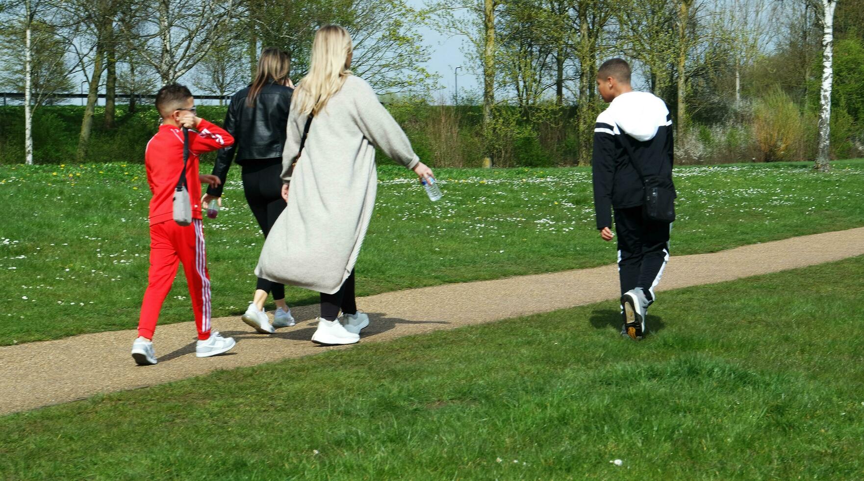 Low Angle View of Willen Lake Park with Local and Tourist Public Enjoying the Beauty of Lake and Park by Walking Around with Their Families. Footage Was Captured on 09-April-2023 at Milton Keynes UK photo