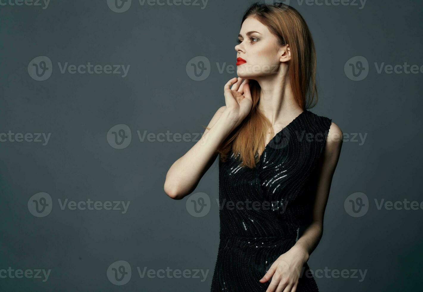 Red-haired lady in a dress on a gray background gestures with her hands Copy Space photo