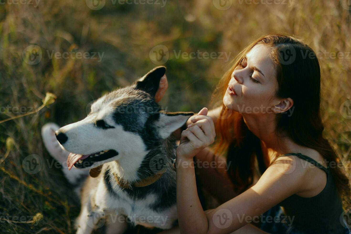 Woman sitting in field with dachshund dog smiling while spending time outdoors with dog friend photo