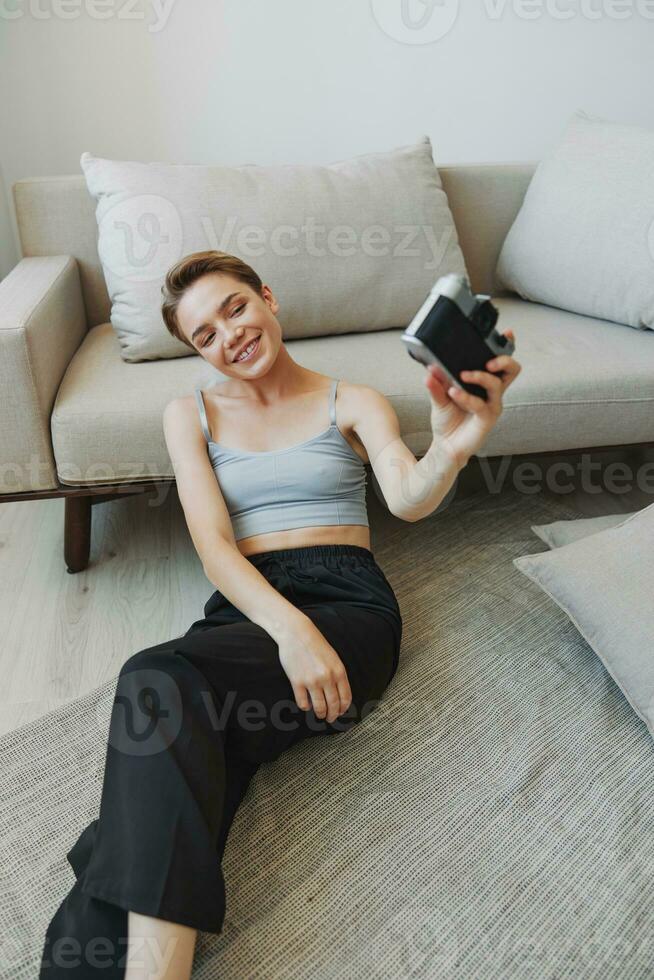 Happy smile woman holding an old camera and taking pictures of herself as a weekend photographer in home clothes with a short haircut hair without filters on a white background, free copy space photo